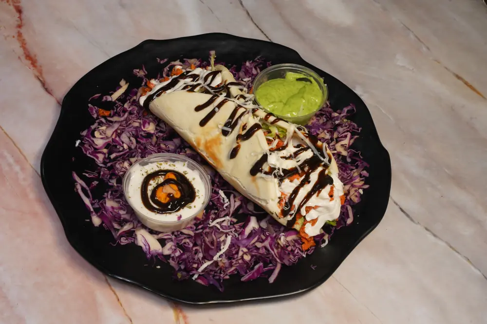 BBQ chicken rumali roti shawarma drizzled with sauce over red cabbage