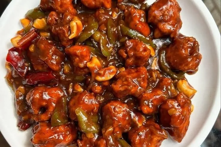 Bohri-style chilli chicken with capsicum and red chillies on a white plate