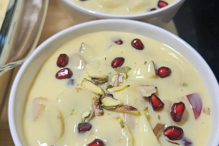 Two bowls of fruit custard topped with pomegranate and pistachio