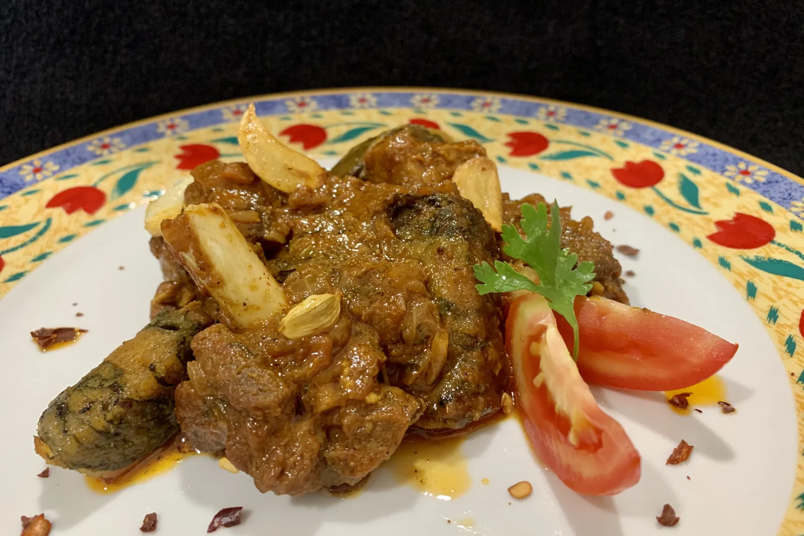 Bohri mutton patvelia, mutton curry with patrel rolls and fried garlic, on a floral plate