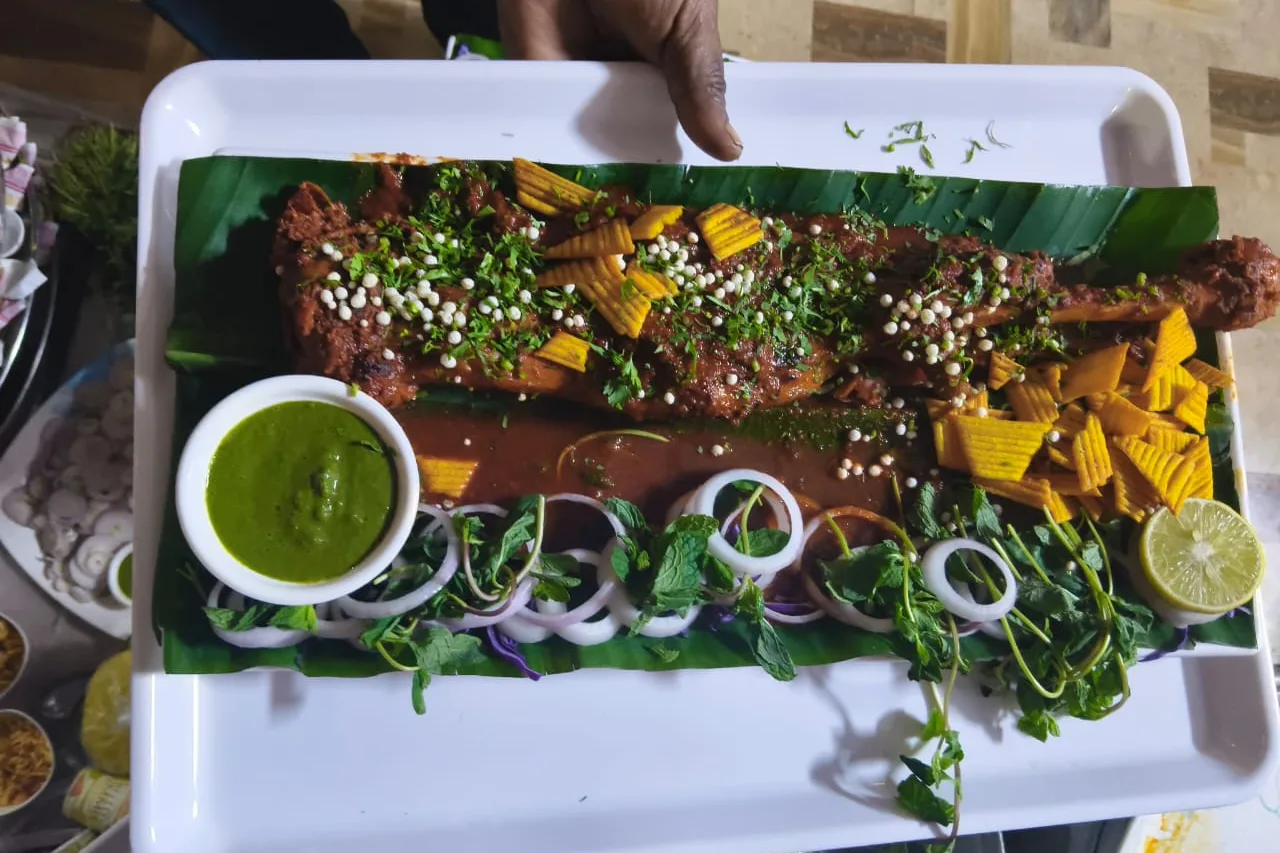 Whole roast mutton raan on a banana leaf with green chutney, onion rings and lemon, from a Nafees catering order