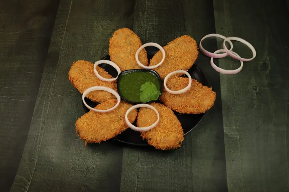 Crumb-fried chicken cutlets arranged around green chutney