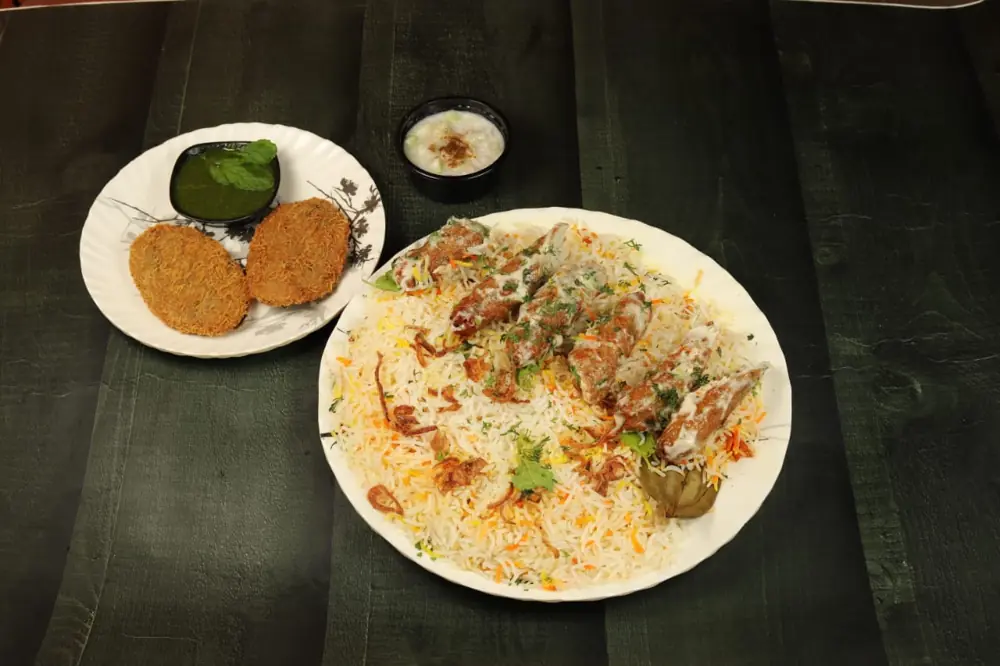Malai seekh kabab biryani in white cream gravy with two cutlets and green chutney