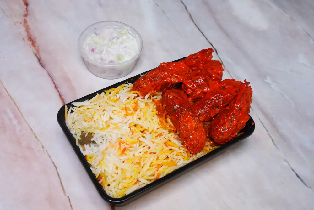 Mutton tandoori seekh kabab biryani packed in a sealed delivery box with raita